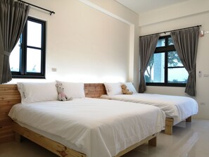A hotel room with two beds, wooden headboards, white bedding, and a view of trees through the windows. - Rural Scenary Villa (Taitung)