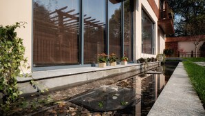 Un bâtiment moderne doté de grandes fenêtres, d’un chemin en pierre et d’un petit élément décoratif aquatique.