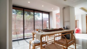 Un espace de restauration moderne avec une table et des chaises en bois, de grandes fenêtres et un parasol rouge en arrière-plan.