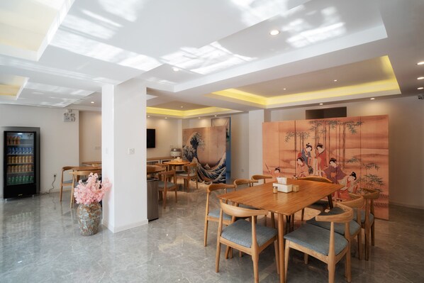 Un espace repas moderne avec une table et des chaises en bois, un vase rempli de fleurs roses et une peinture japonaise traditionnelle accrochée au mur.
