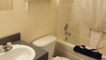 A bathroom with a white sink, toilet, and bathtub. There is a shelf above the sink with toiletries.
