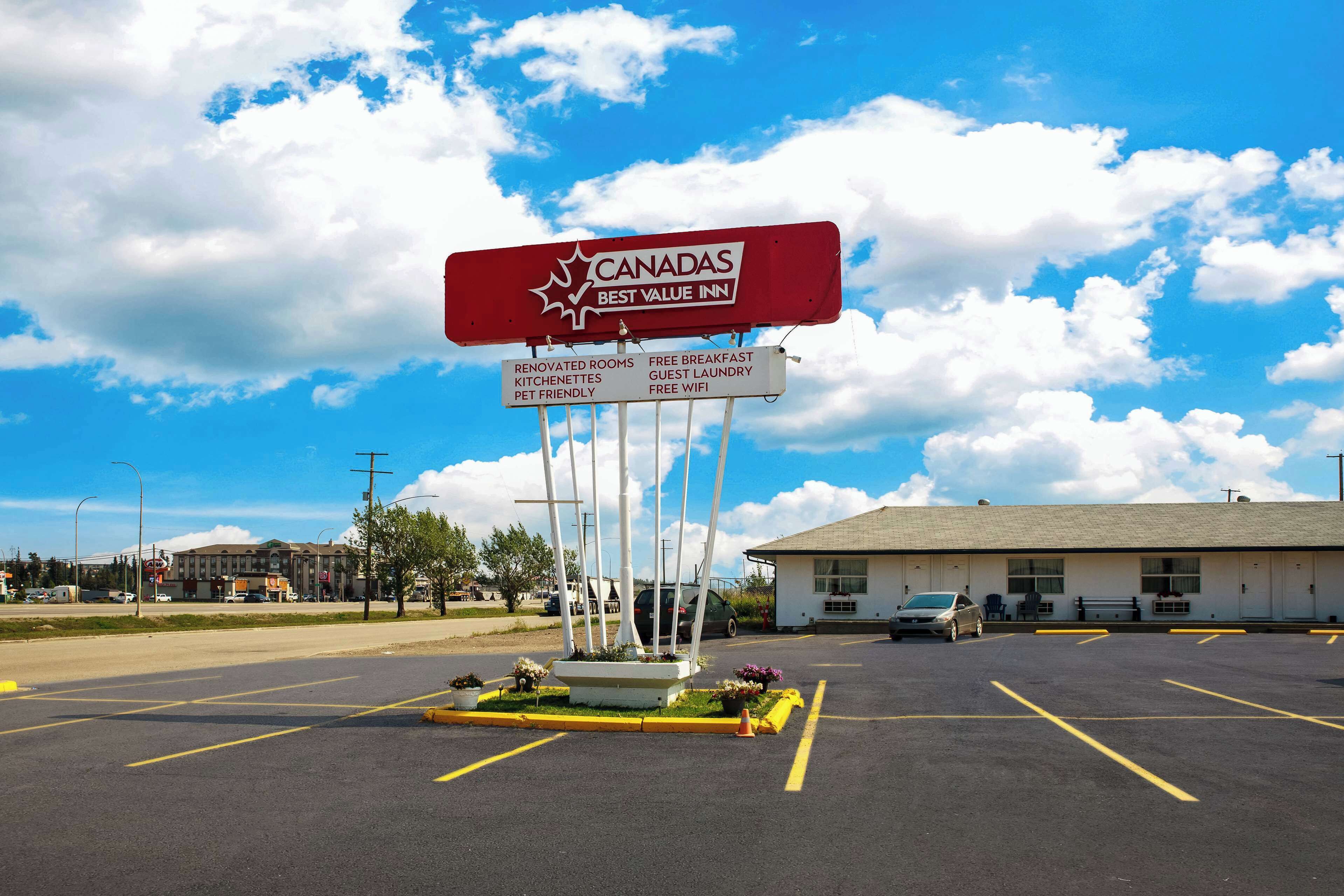 A parking lot with a sign for Canada's Best Value Inn, featuring amenities like renovated rooms, free breakfast, and guest laundry.