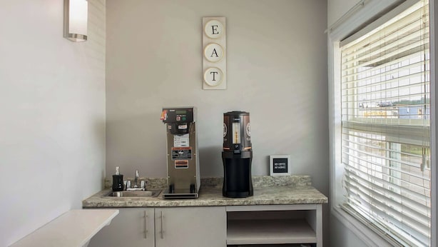 Ett litet kök med en kaffemaskin, en kaffedispenser och en skylt med texten ”ÄT”.