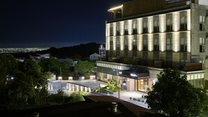 Et moderne hotel med glasfacade, flere etager og en tagterrasse.