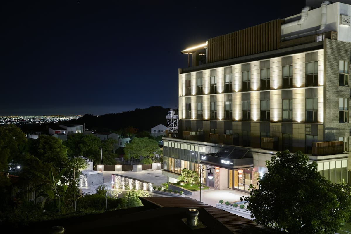 Ein modernes Hotel mit Glasfassade, mehreren Etagen und einer Dachterrasse.