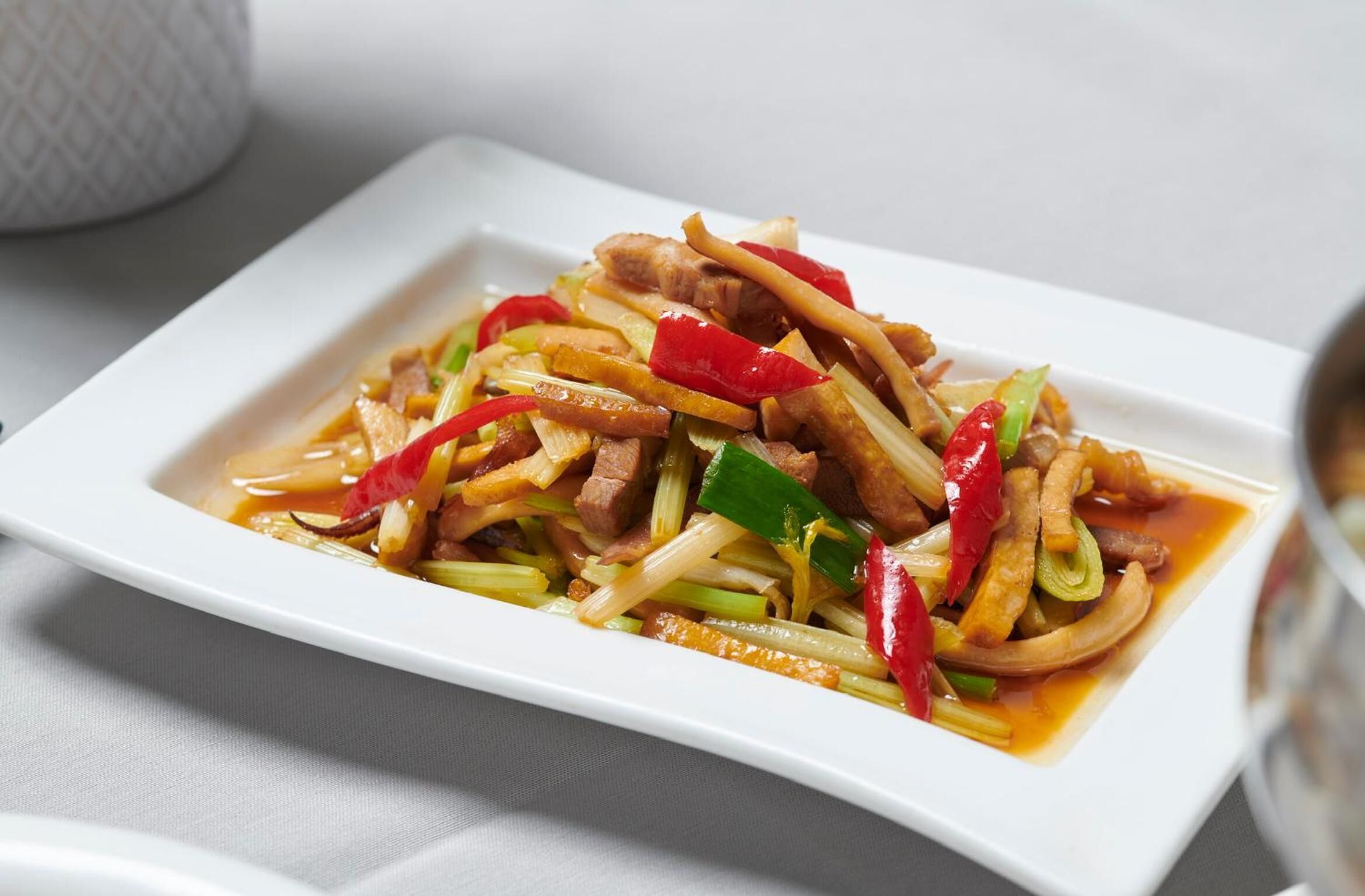 A dish of stir-fried meat and vegetables on a white plate.