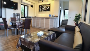 A modern hotel lobby with a sofa, chairs, a coffee table, a TV, a coffee machine, and a large painting on the wall. - Matsu A Nan Jing B&B (Beigan)