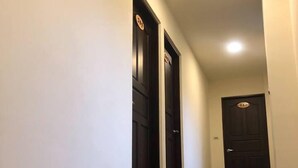 A hallway with dark wooden flooring and white walls. There are three doors, each with a number plate above it. - Matsu A Nan Jing B&B (Beigan)