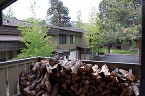 A stack of firewood on a balcony overlooking a residential area with houses and trees. - Amazing Retreat in Heart of Mammoth (Mammoth Lakes)