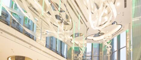 A modern interior with a spacious atrium, reflective surfaces, and contemporary lighting fixtures.