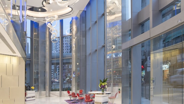 Un interior moderno con una zona de estar central, ventanas amplias y un diseño de techo llamativo.