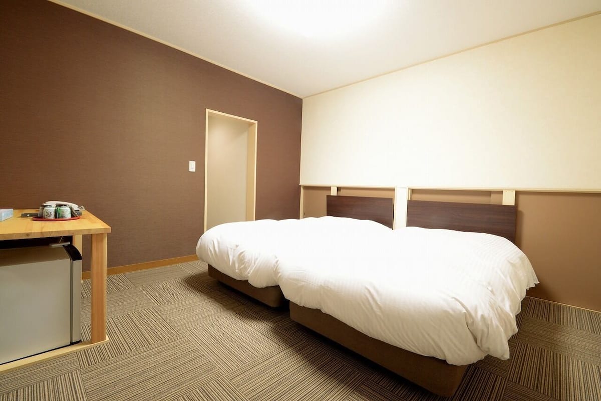 Una habitación de hotel con una cama, un escritorio y un refrigerador pequeño.