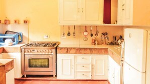 A compact kitchen with white cabinets, a gas stove, an oven, and a refrigerator. - Kamaki House (Naivasha)
