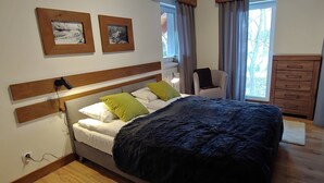Un dormitorio con cama, cómoda y dos cuadros en la pared.
