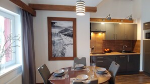 Una cocina moderna con armarios oscuros, horno empotrado y comedor con una mesa dispuesta para cuatro.