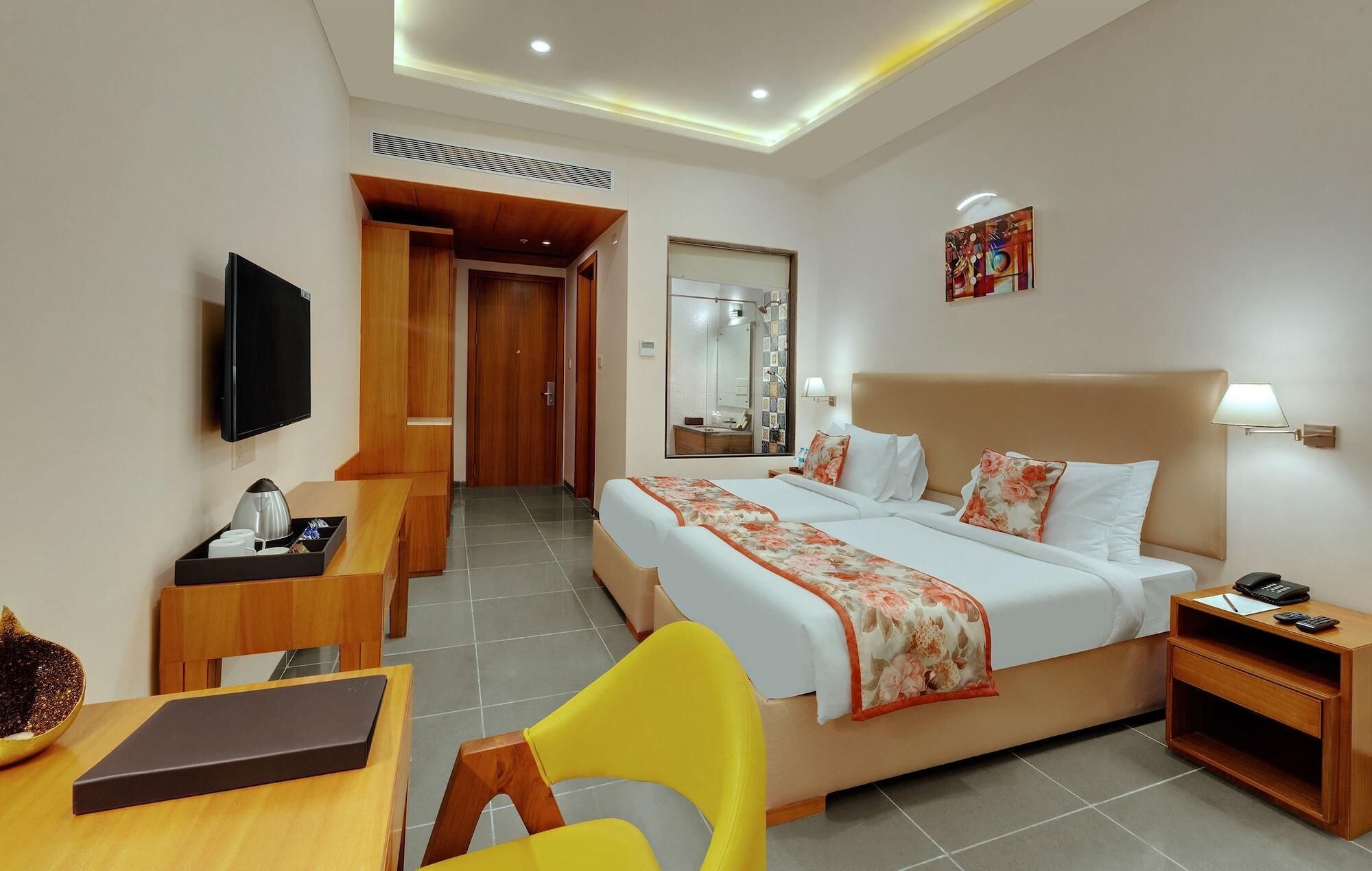 A hotel room with a bed, bedside table, chair, desk, and a television.