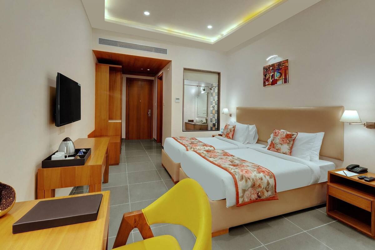 Une chambre d’hôtel comprenant un lit, une table de chevet, une chaise, un bureau et un téléviseur.