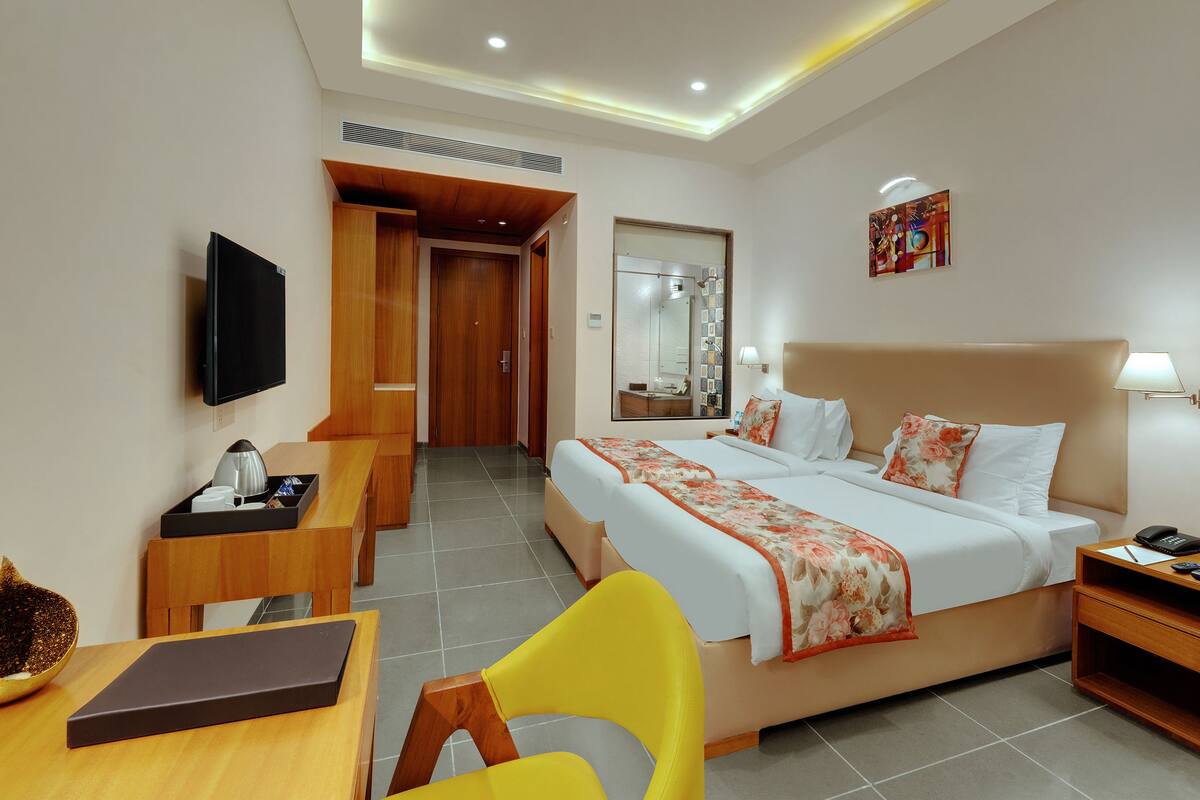 Une chambre d’hôtel comprenant un lit, une table de chevet, une lampe, une télévision et un bureau avec une chaise.