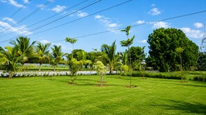 A well-maintained grassy area with young trees and a clear sky. - Malhaar Resort (Dahegam)