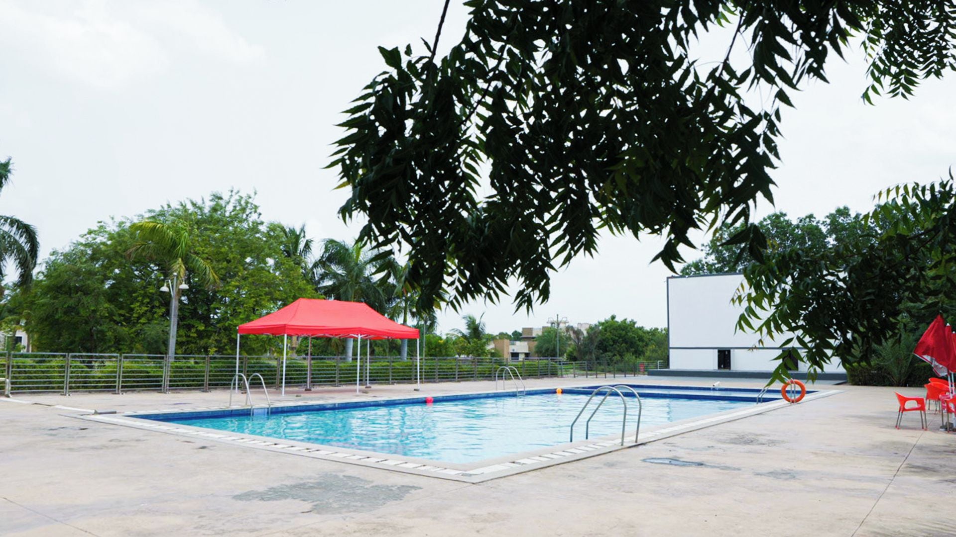 A swimming pool with a red canopy and a white building in the background.
