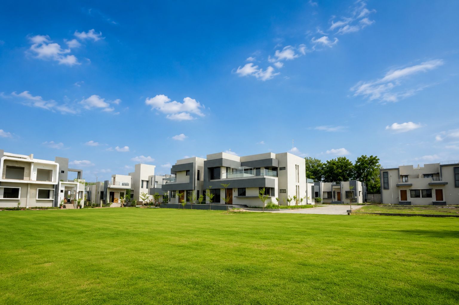 A modern residential complex with multiple two-story buildings, a well-maintained lawn, and a clear blue sky.
