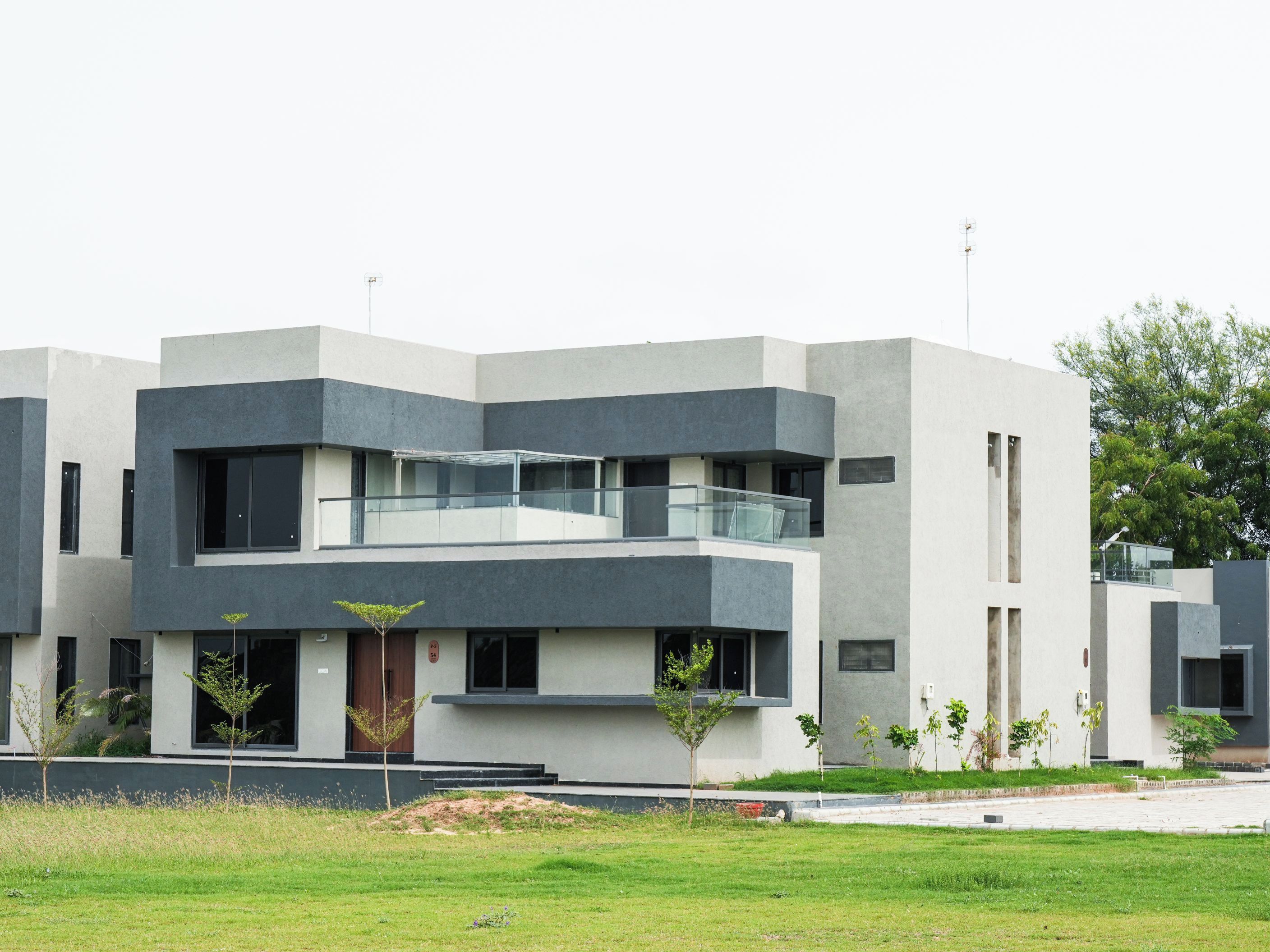 A modern multi-story building with a flat roof, large windows, and a balcony on the second floor.