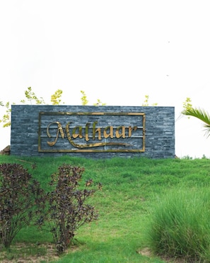 A stone wall with the name 'Mahzar' in gold lettering. - Malhaar Resort (Dahegam)