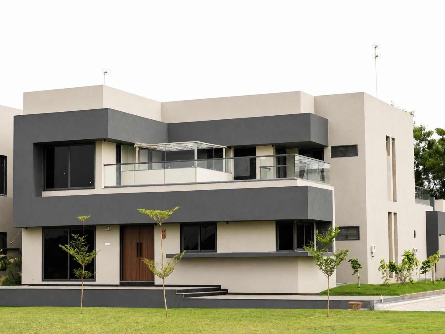 A modern multi-story residential building with a flat roof, large windows, and a balcony.