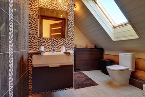 A modern bathroom with a skylight, a sink with two towel racks, and a dark wooden cabinet. - EverySky Kowary Dom z Bali (Kowary)