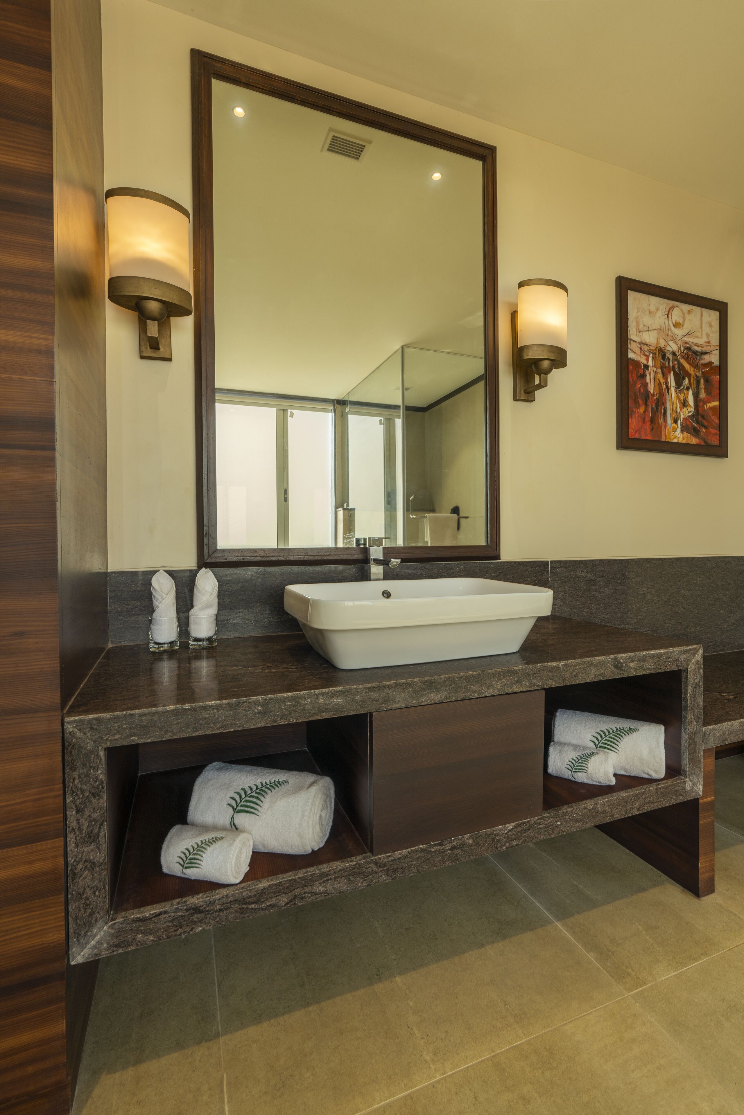 A bathroom with a large mirror, a white sink, and two towel racks with folded towels.