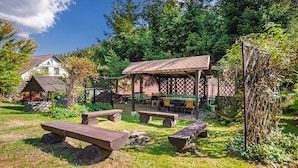 An outdoor picnic area with wooden benches and a covered seating area.