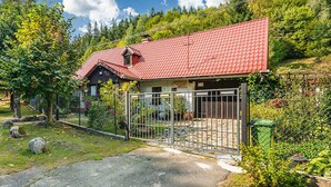 A house with a red tiled roof, a fenced yard, and a gravel driveway.