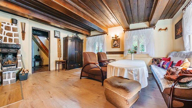 A cozy living room with a fireplace, wooden floors, a dining table, and comfortable seating.
