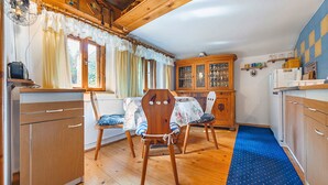 A cozy kitchen with wooden cabinets, a dining table with chairs, and a blue patterned rug.