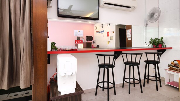 A modern kitchen with a red countertop, a coffee machine, a TV mounted above the counter, and a wall-mounted fan.