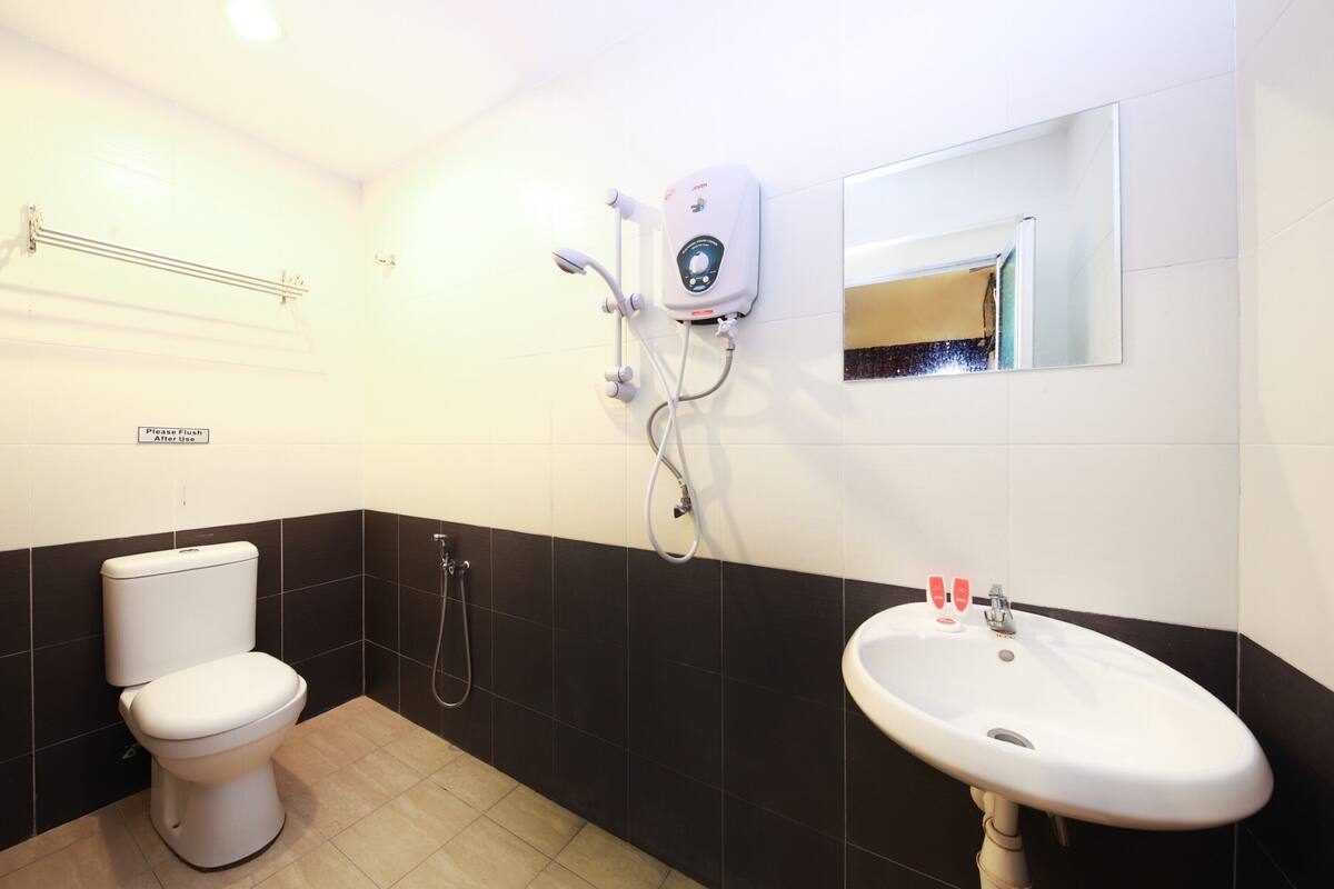 A bathroom with a toilet, a sink, a shower, and a hand dryer.
