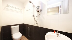 A bathroom with a toilet, a shower unit, and a sink.