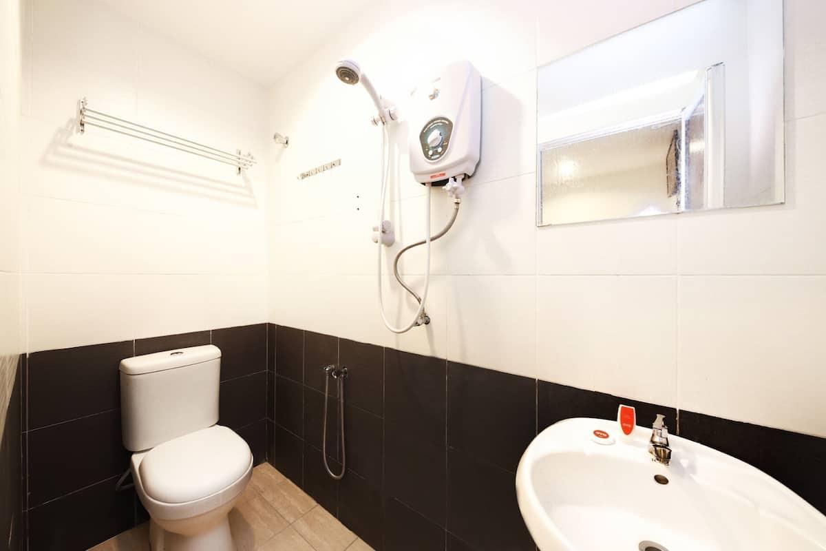 A bathroom with a toilet, a shower unit, and a sink.
