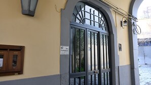 A building entrance with a stone-paved path, a metal gate, and a wall-mounted sign. - B&B Palummelle (Naples)