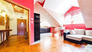 Een moderne loftkamer met een houten vloer, een zwart schapenkast, een witte bank en een rode accentmuur.