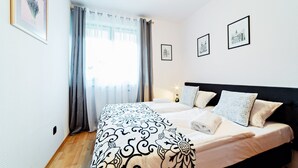Un dormitorio con cama, cortinas e imágenes enmarcadas en la pared.