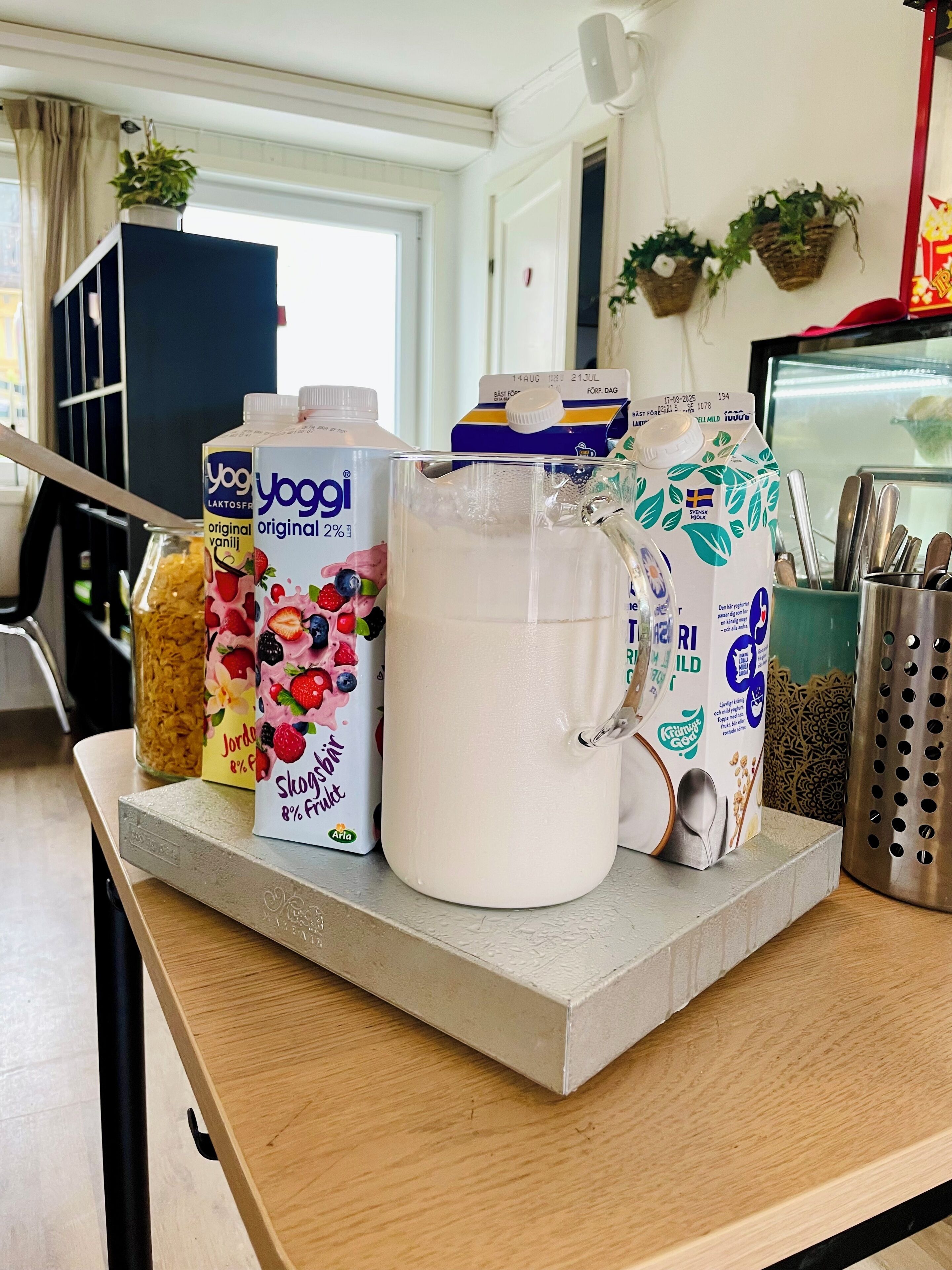 Una encimera de cocina con una jarra de leche, cajas de cereales y una cafetera.