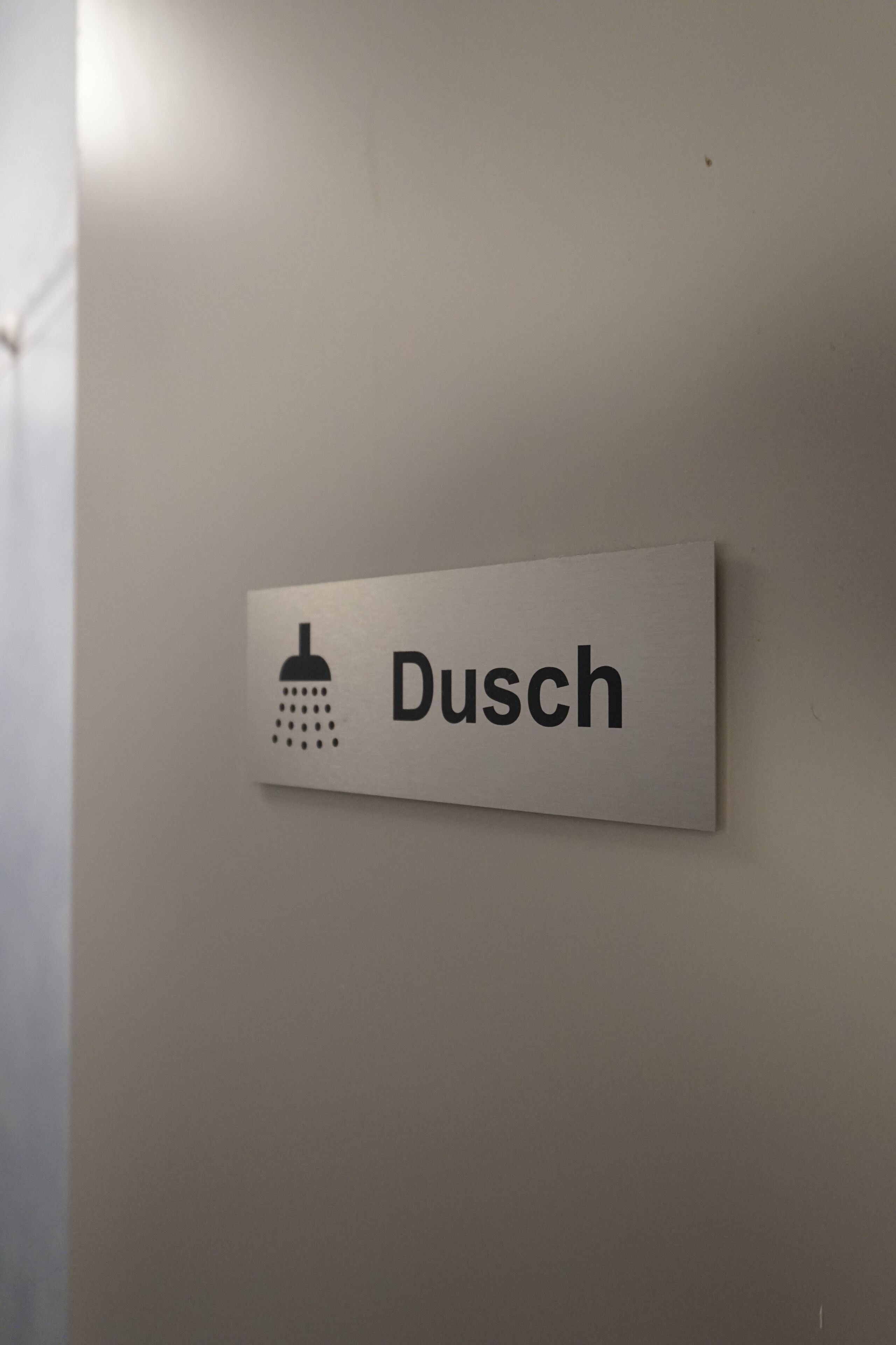 A sign with a shower icon and the word 'Dusch' indicating a shower area.