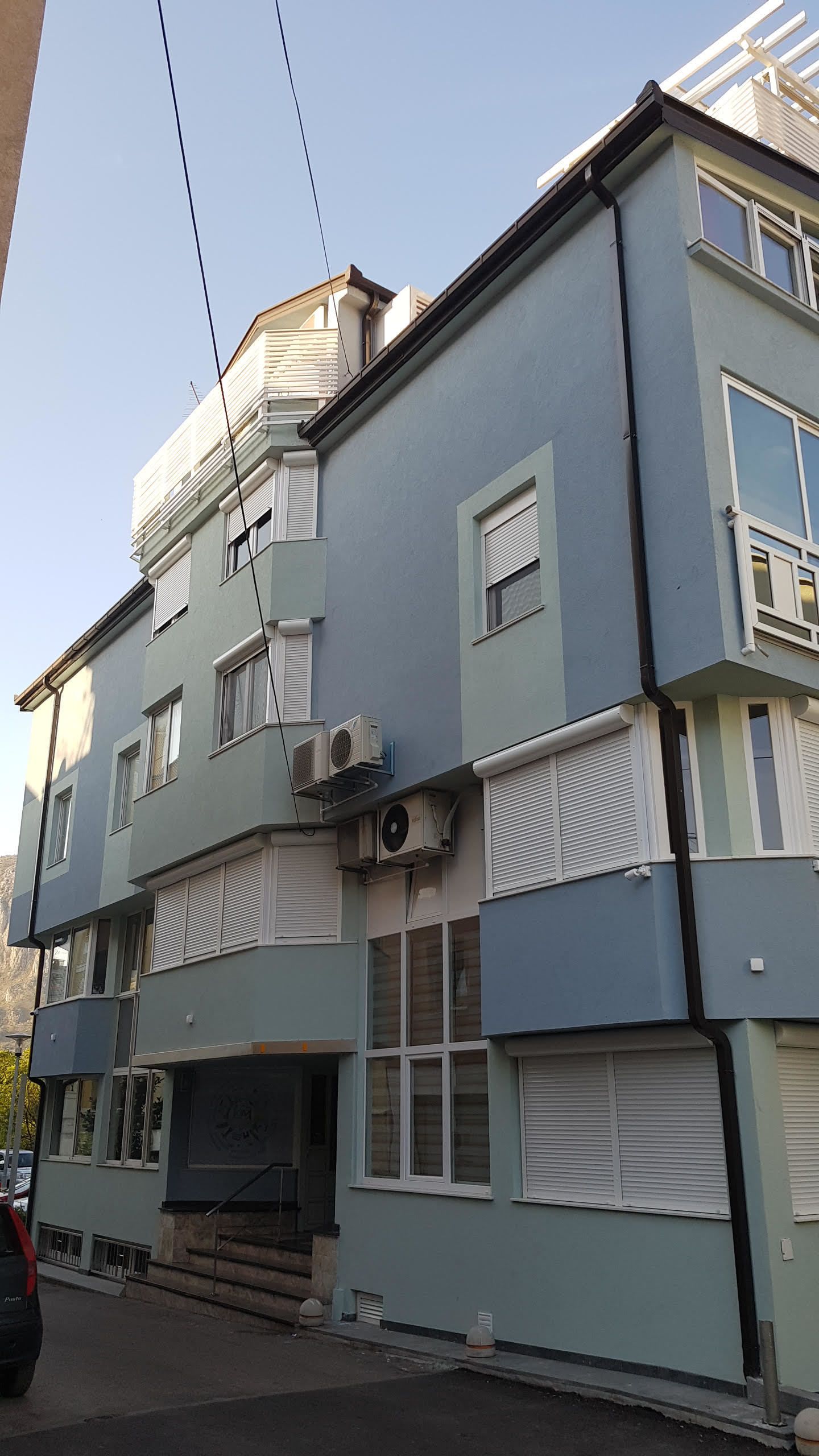 Een meerhoog gebouw met een plat dak, meerdere ramen en airconditioningsapparaten.
