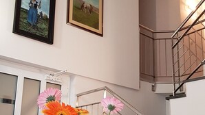 A dining area with a table, a vase with flowers, and a staircase with a railing. - Galeria Nura (Mostar)