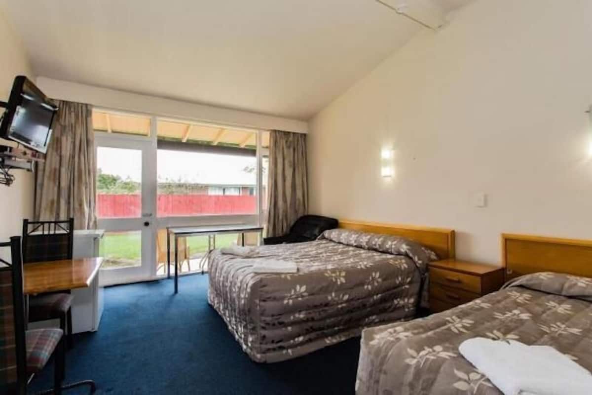 Une chambre d’hôtel avec deux lits, un bureau, une chaise et un téléviseur.