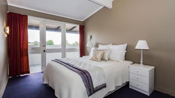 Een slaapkamer met een bed, nachtkastjes en uitzicht door een schuifdeur.