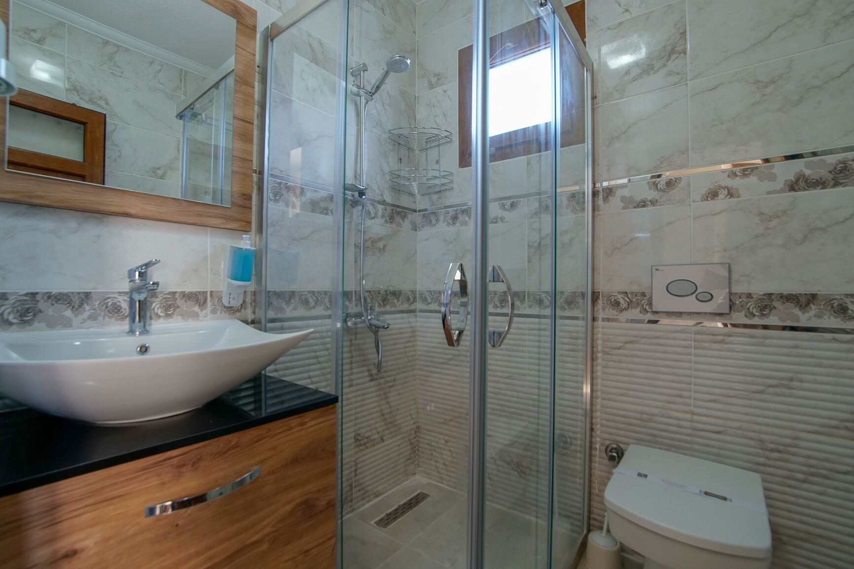 A modern bathroom with a glass-enclosed shower, a white sink, and a toilet.