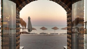 A beach view through a stone archway with umbrellas and lounge chairs. - Cuhadar Ahsap Evleri (Datça)
