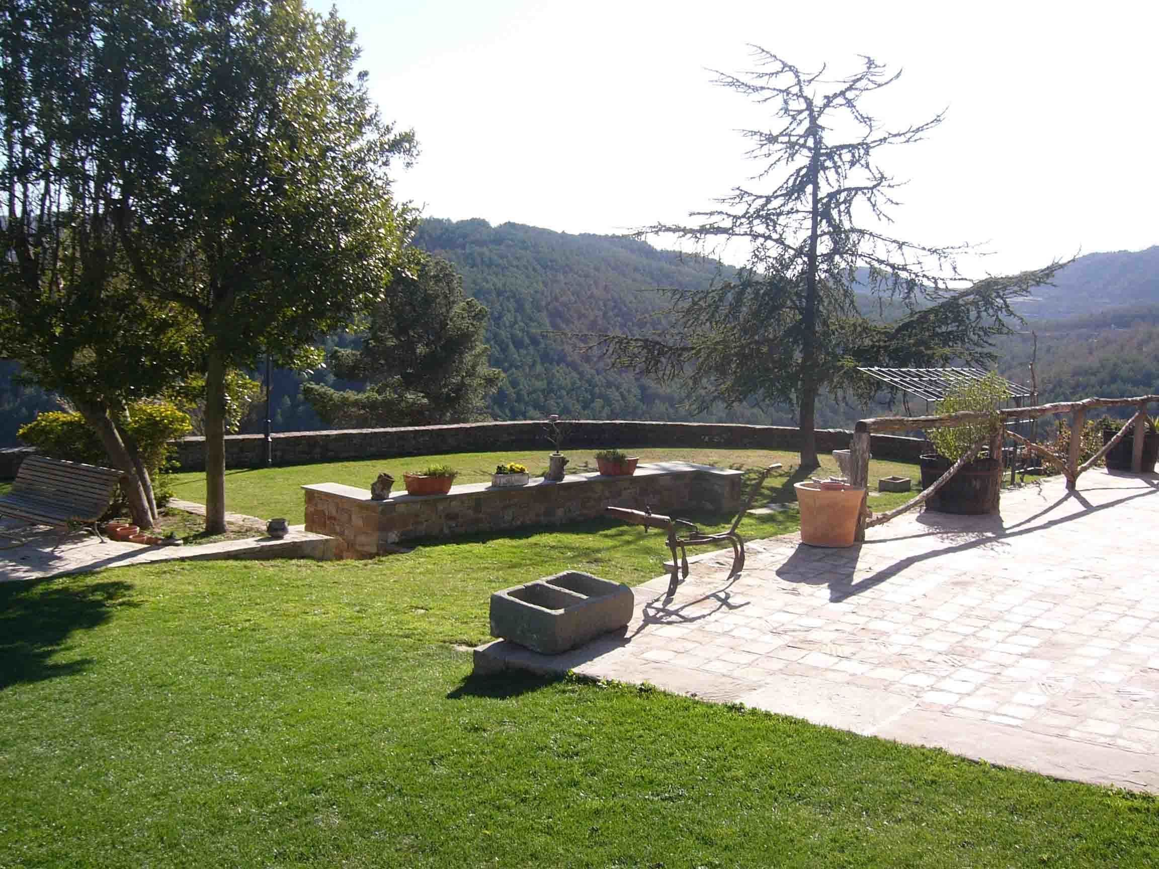 Un patio con suelo de piedra, mobiliario exterior y plantas en macetas.